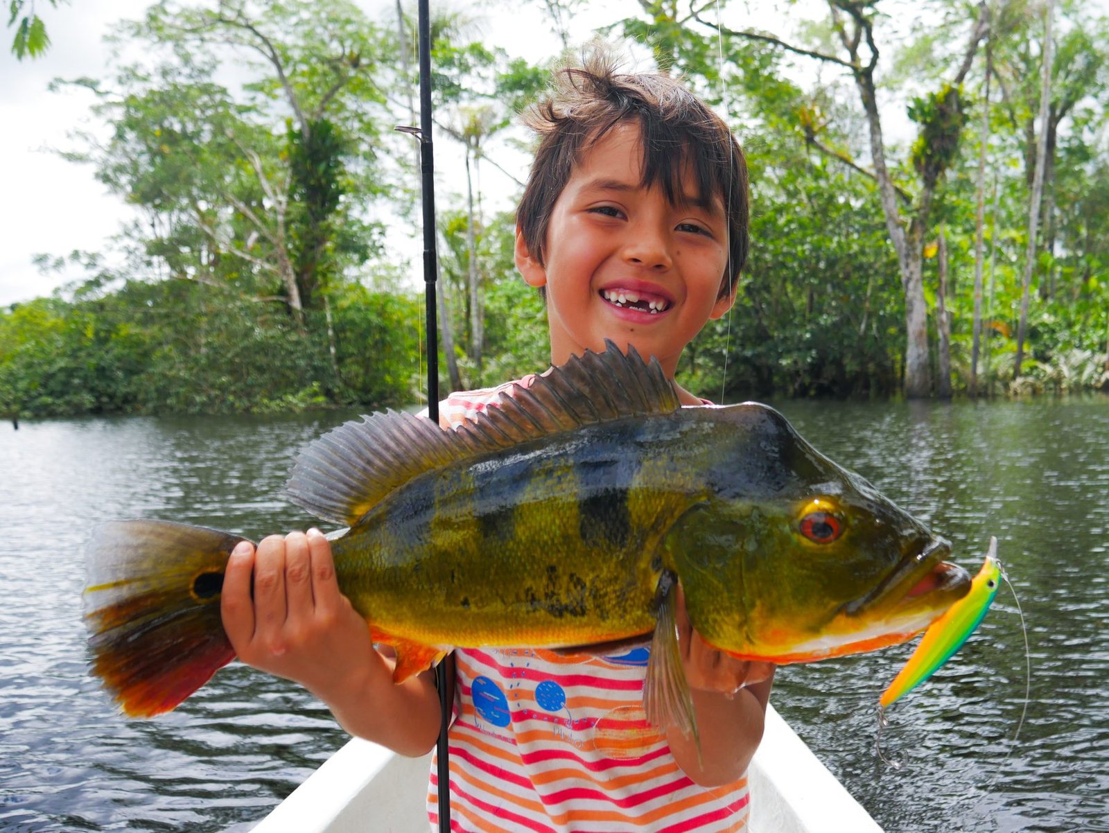 Young angler proudly holding a peacock bass